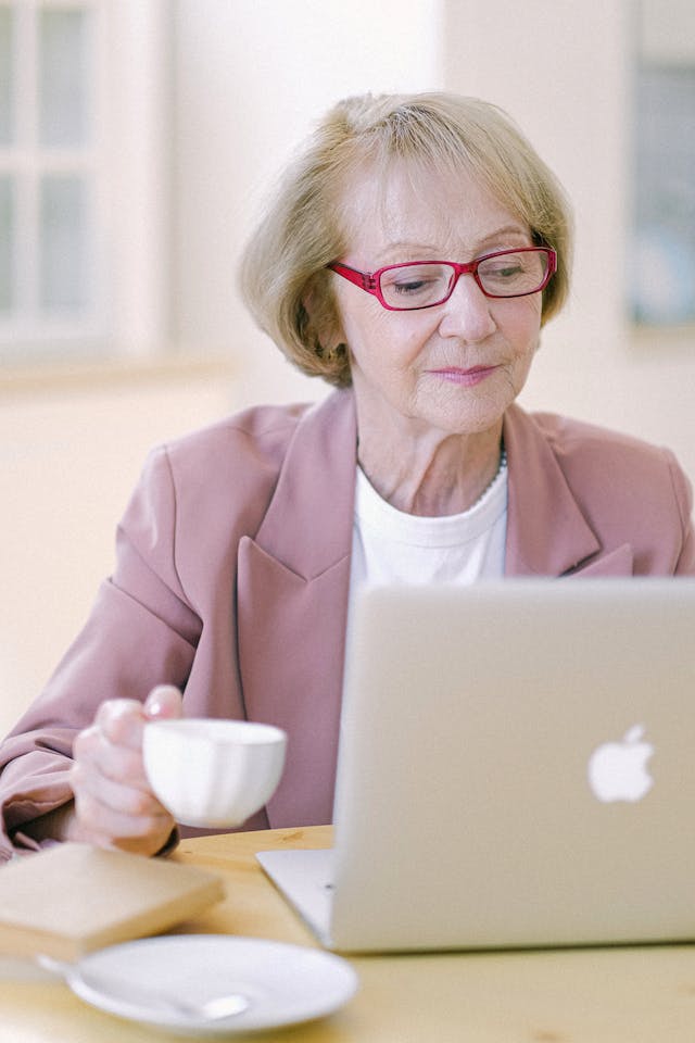 online wills, senior woman using a laptop while holding from a coffee or tea cup