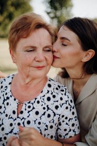 elder financial abuse, image of woman pecking an older woman on the cheek